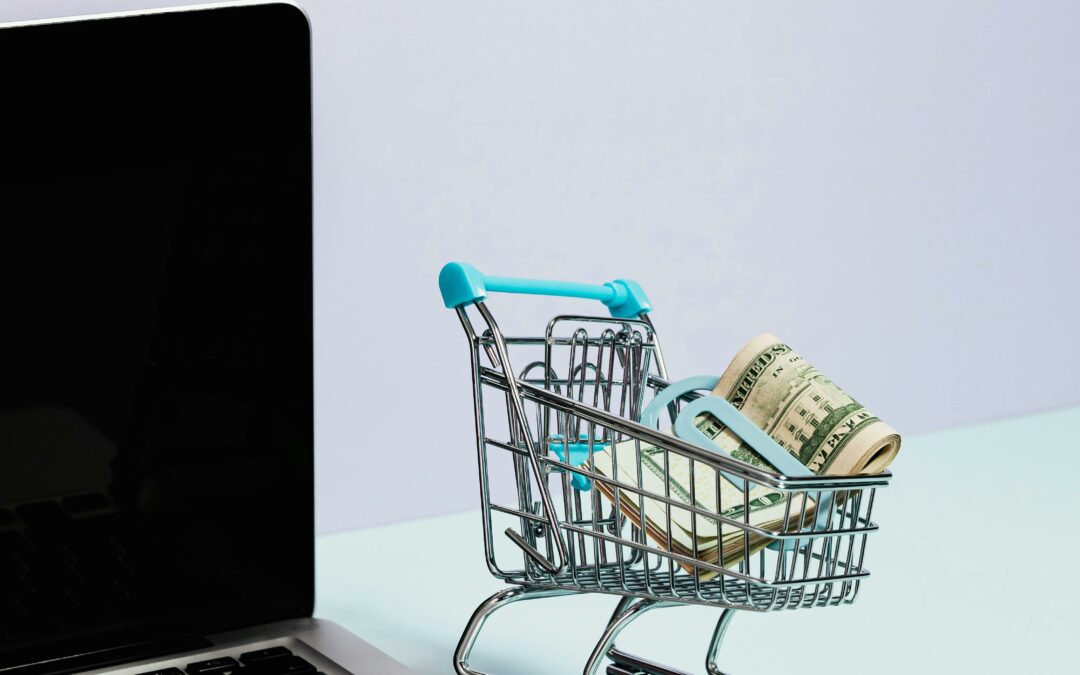 computer with tiny shopping cart with money in it